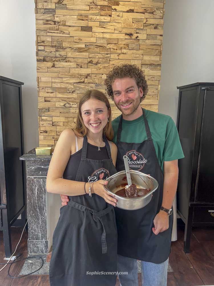Couple making Belgian chocolate truffles together during a chocolate workshop in Brussels, surrounded by handmade chocolates and baking tools.