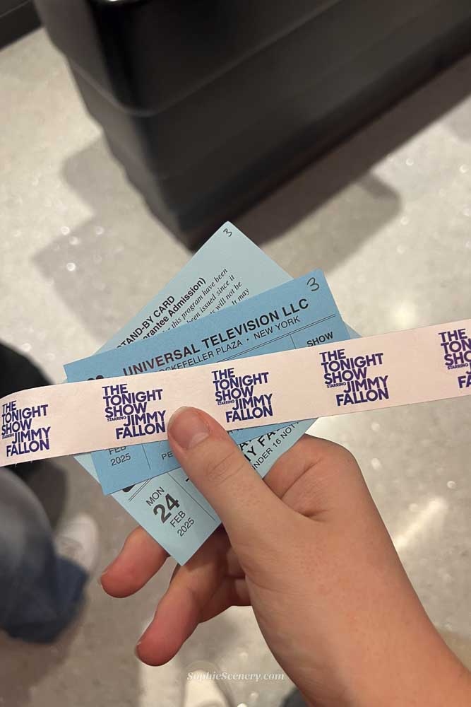 Hand holding tickets for The Tonight Show Starring Jimmy Fallon at NBC Studios in Rockefeller Center, New York City.