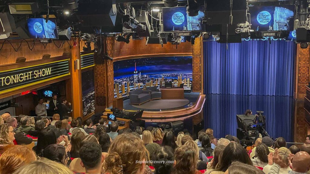 Audience view of The Tonight Show Starring Jimmy Fallon set in New York City, showing the stage, cameras, studio lights, and seated crowd before a live taping.
